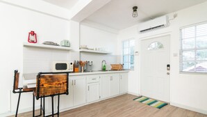A modern kitchen with white cabinets, a wooden chair, and a built-in microwave. - The Barnyard is a chic, cozy open concept studio apartment.  (Sion Hill)