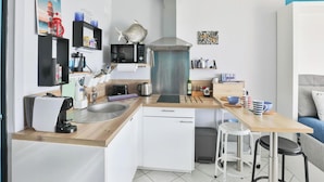 Uma cozinha compacta com cafeteira, micro-ondas, torradeira, pia e um pequeno espaço de refeições com banquetas.