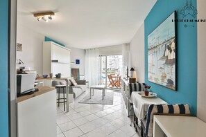 A modern apartment with a kitchen, dining area, and living room. There is a balcony with a view of the city.