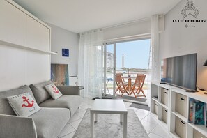A modern living room with a sofa, coffee table, TV, and a balcony with a table and chairs.