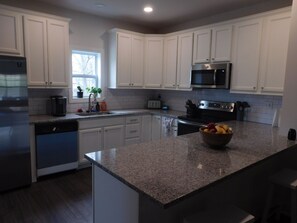 A modern kitchen with white cabinets, a granite countertop, stainless steel appliances, and a window providing natural light. - Family-friendly home, dedicated workspace, minutes from Cincinnati attractions! (Cincinnati)