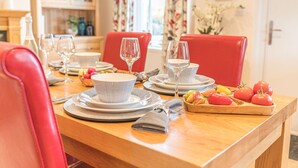 Tavolo da pranzo apparecchiato con ciotole, piatti e posate a motivi bianchi e neri, insieme a un vassoio di legno con pomodori e peperoni.