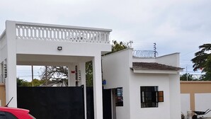 A building with a white facade, a covered entrance, and a small adjacent structure. - Diani Bliss-Where Luxury Meets the Ocean Breeze.” (Mombasa)