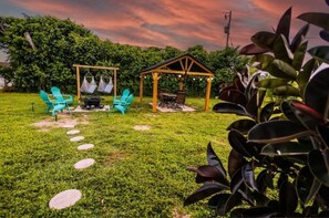 Relax in a serene outdoor space surrounded by lush greenery and a shaded pergola.