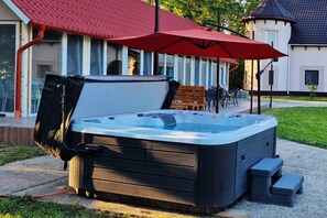 Relax in the outdoor hot tub, surrounded by a seating area with a bench and chairs.