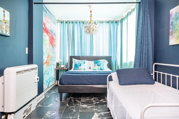 Une chambre à coucher avec un lit, des tables de chevet, un radiateur et une fenêtre avec des rideaux.