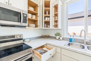A kitchen with a microwave, oven, and open cabinets with dishes. - Sea forever (Ocean Shores)