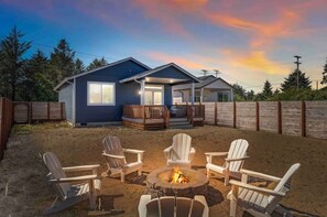 A cabin with a fire pit and Adirondack chairs in the backyard. - Sea forever (Ocean Shores)