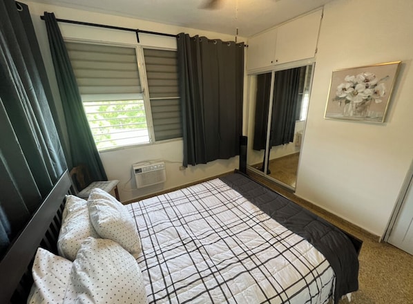 A bedroom with a bed, a window with curtains, a radiator, a mirror, and a framed picture on the wall. - Spacious San Juan Full Floor Apartment (San Juan)
