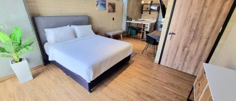 Un dormitorio moderno con una cama grande, un escritorio pequeño y una planta en maceta.