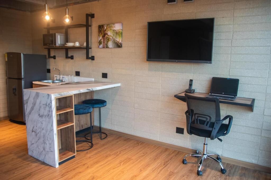 A modern kitchen with a marble island, a built-in microwave, and a flat-screen TV mounted on the wall.