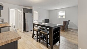 Een moderne keuken met een centraal eiland, barkrukken, een koelkast en een eetgedeelte met een stoel.