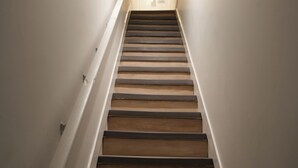 Een trap met houten treden en witte muren.