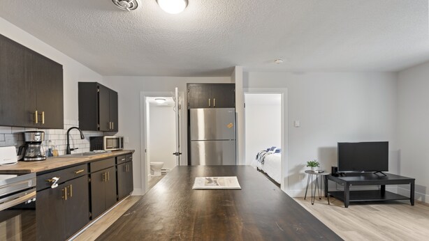 Een moderne keuken met donkere kastjes, roestvrijstalen apparatuur en een houten eiland.