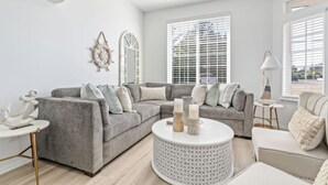 A modern living room with a grey sectional sofa, a round coffee table, and a small side table. - Beach Happy (Ocean Shores)