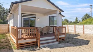 A single-story house with a covered porch, a small deck, and a fenced backyard. - Beach Happy (Ocean Shores)