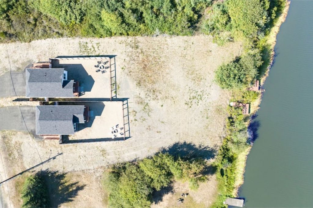 An aerial view of a property with two buildings, a dock, and a lake.