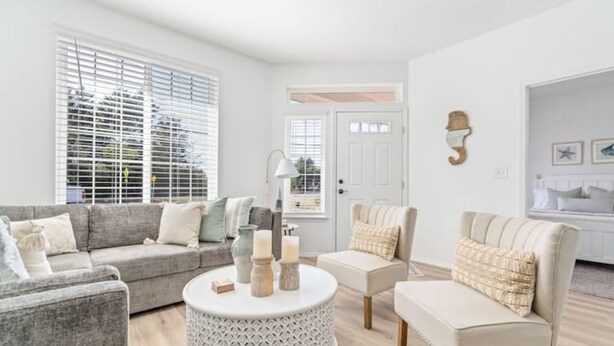 A modern living room with a grey sofa, a round coffee table with candles, and a beige armchair. - Beach Happy (Ocean Shores)