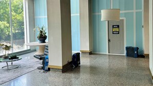 Eine geräumige Lobby mit hoher Decke, großen Fenstern und einer Sitzecke mit Tisch und Stühlen.