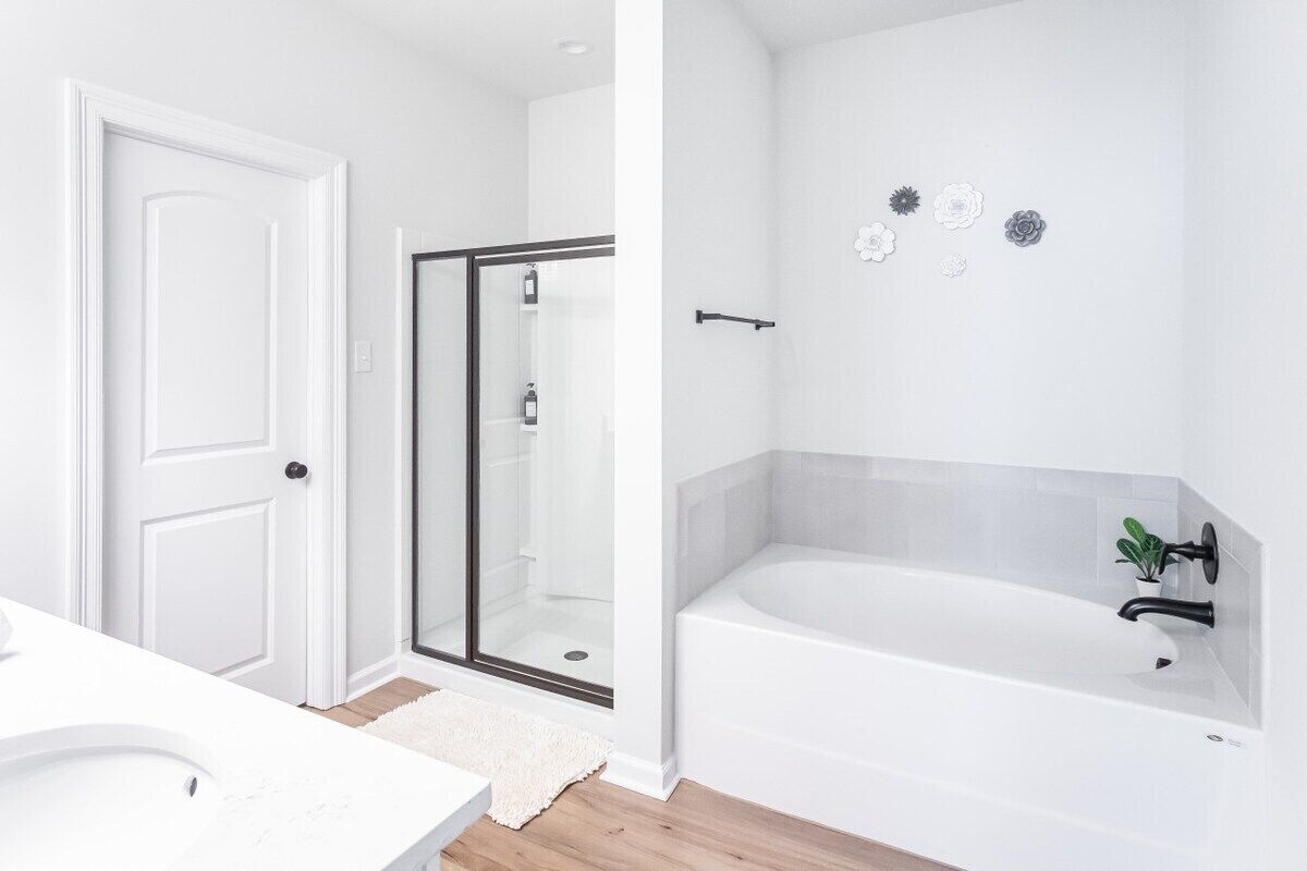 A modern bathroom with a shower, a bathtub, and a white sink.