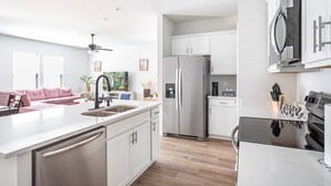 A modern kitchen with a central island, stainless steel appliances, and white cabinetry. - La Vida Loca Stay in Baton Rouge near LSU - BC1011 (Baton Rouge)