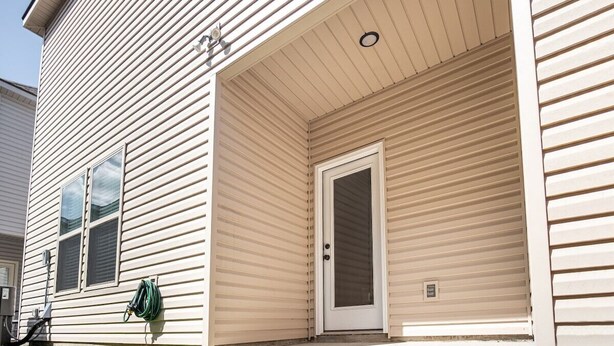 A residential building with a closed garage door, a visible window, and a hose coiled against the wall. - La Vida Loca Stay in Baton Rouge near LSU - BC1011 (Baton Rouge)