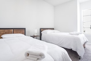 Een hotelkamer met twee bedden, een nachtkastje, een lamp en een raam.