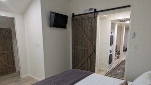 Une chambre avec un lit, un téléviseur fixé au mur et une porte coulissante de style grange.