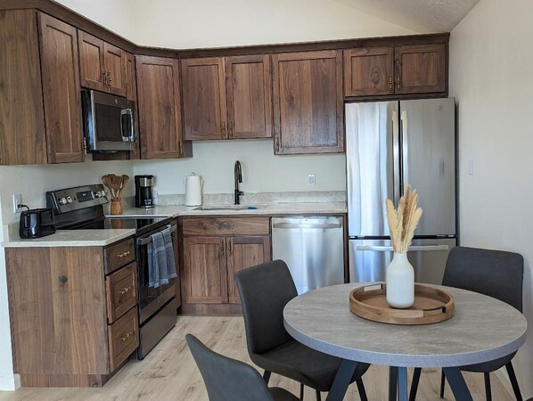 Una cocina moderna con armarios de madera, electrodomésticos de acero inoxidable y una mesa redonda con sillas.