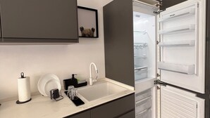 A modern kitchen with a built-in dishwasher, a sink, and a mirror above it. - White Door Apartments (Haifa)
