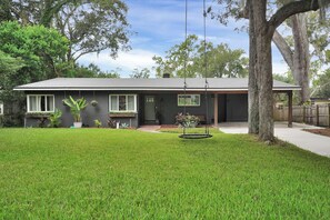 Enjoy a serene home with a lush lawn, mature trees, and a cozy front porch.
