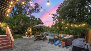 A patio with hexagonal stone flooring, outdoor furniture, string lights, and a view of a lake.