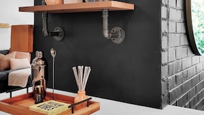 A modern kitchen with exposed brick walls, wooden shelves, and a marble countertop.
