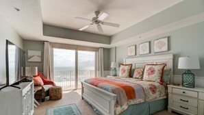 Un dormitorio con cama, mesita de noche, cómoda, silla, ventana con vista y ventilador de techo.
