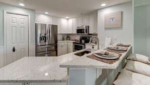 Una cocina moderna con armarios blancos, electrodomésticos de acero inoxidable y encimera de granito.