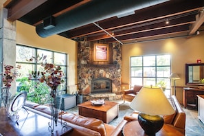 A cozy living room with a stone fireplace, leather sofas, and a coffee table. - Pet-Friendly Silver Mountain Studio: Mountain View (Kellogg)