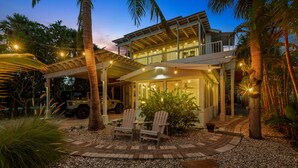 Une maison à deux étages dotée d’un patio couvert, d’un espace salon extérieur et d’un véhicule garé à proximité.