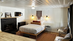 A modern bedroom with a bed, bedside tables, a fireplace, and a dining area. - Cabin 2 "Los Burros" (Pinetop)