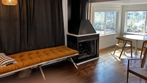 A cozy living room with a sofa, a fireplace, and a dining area with chairs.