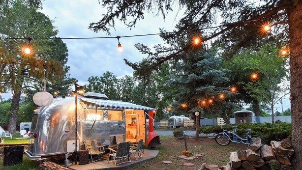 Une maison mobile dotée d’un patio couvert, de meubles d’extérieur et de guirlandes lumineuses.