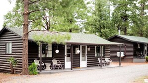 A log cabin with a porch, outdoor seating, and a sign indicating room number 01. - Cabin 1 "Family Cabin" (Pinetop)