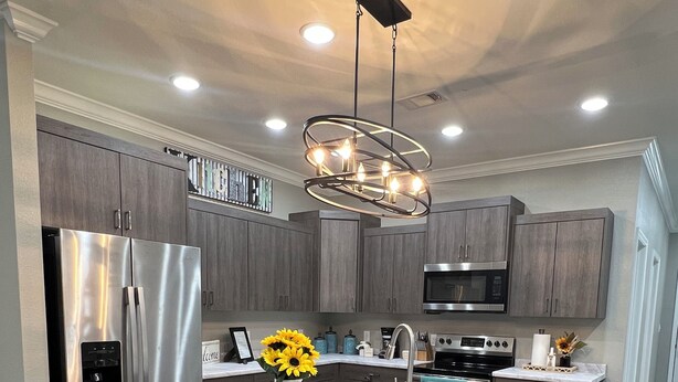 A modern kitchen with a central island, stainless steel appliances, and a pendant light fixture.