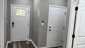 A hallway with two white doors, a window with a view, and a light fixture on the ceiling.