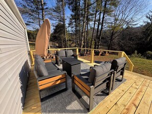 A deck with outdoor furniture, including sofas and a table, surrounded by a wooden railing and a covered area.