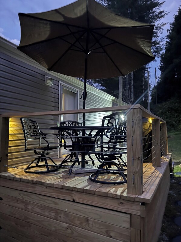An outdoor deck with a table and chairs, an umbrella, and a railing.
