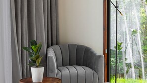 Un salon moderne avec un canapé gris, une petite table ronde en bois sur laquelle est posée une plante, et un lampadaire.