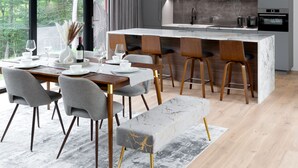 Une cuisine moderne avec des meubles gris, un plan de travail en marbre et un four encastré.