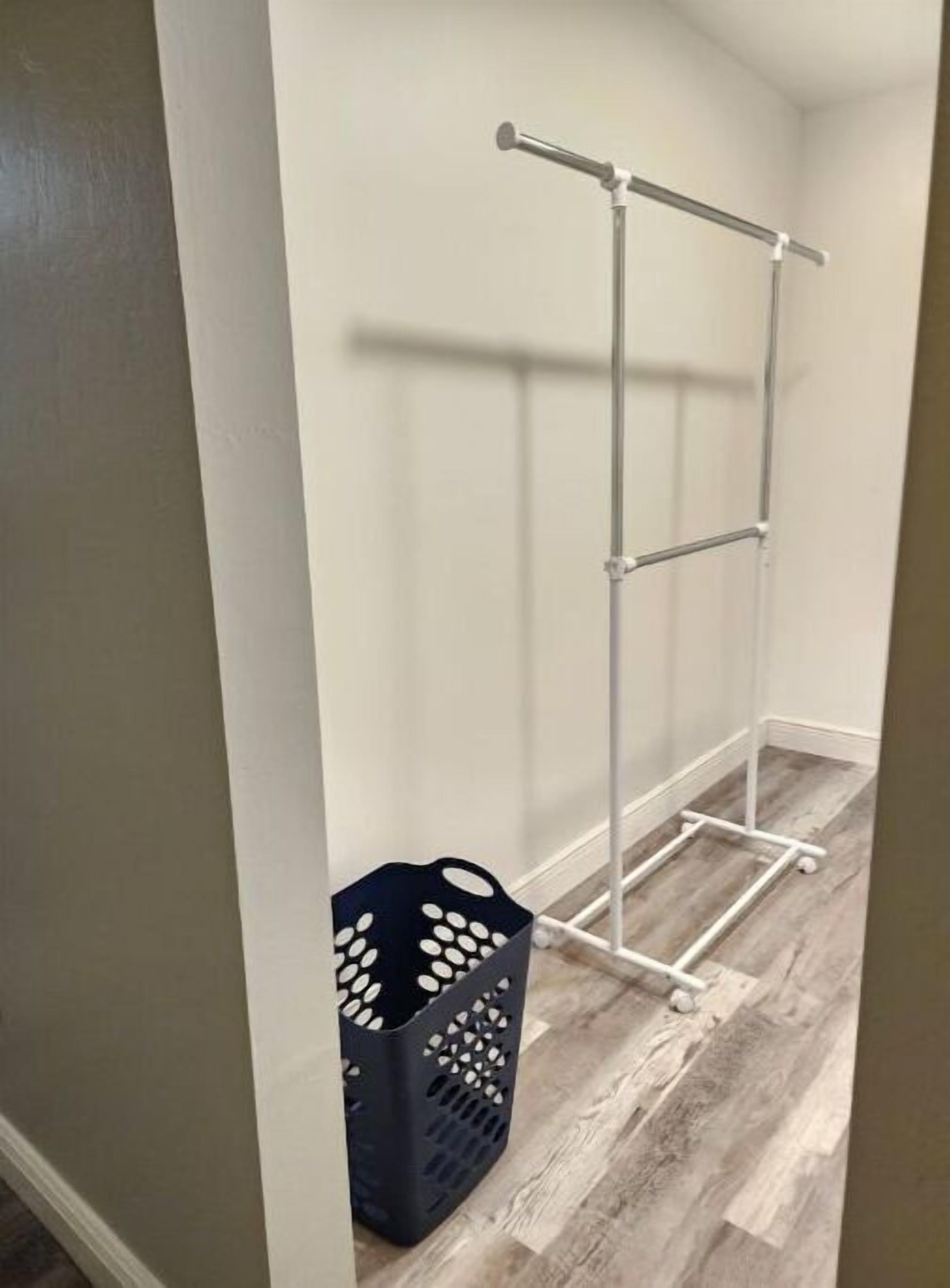 A laundry area with a metal drying rack and a blue laundry basket.
