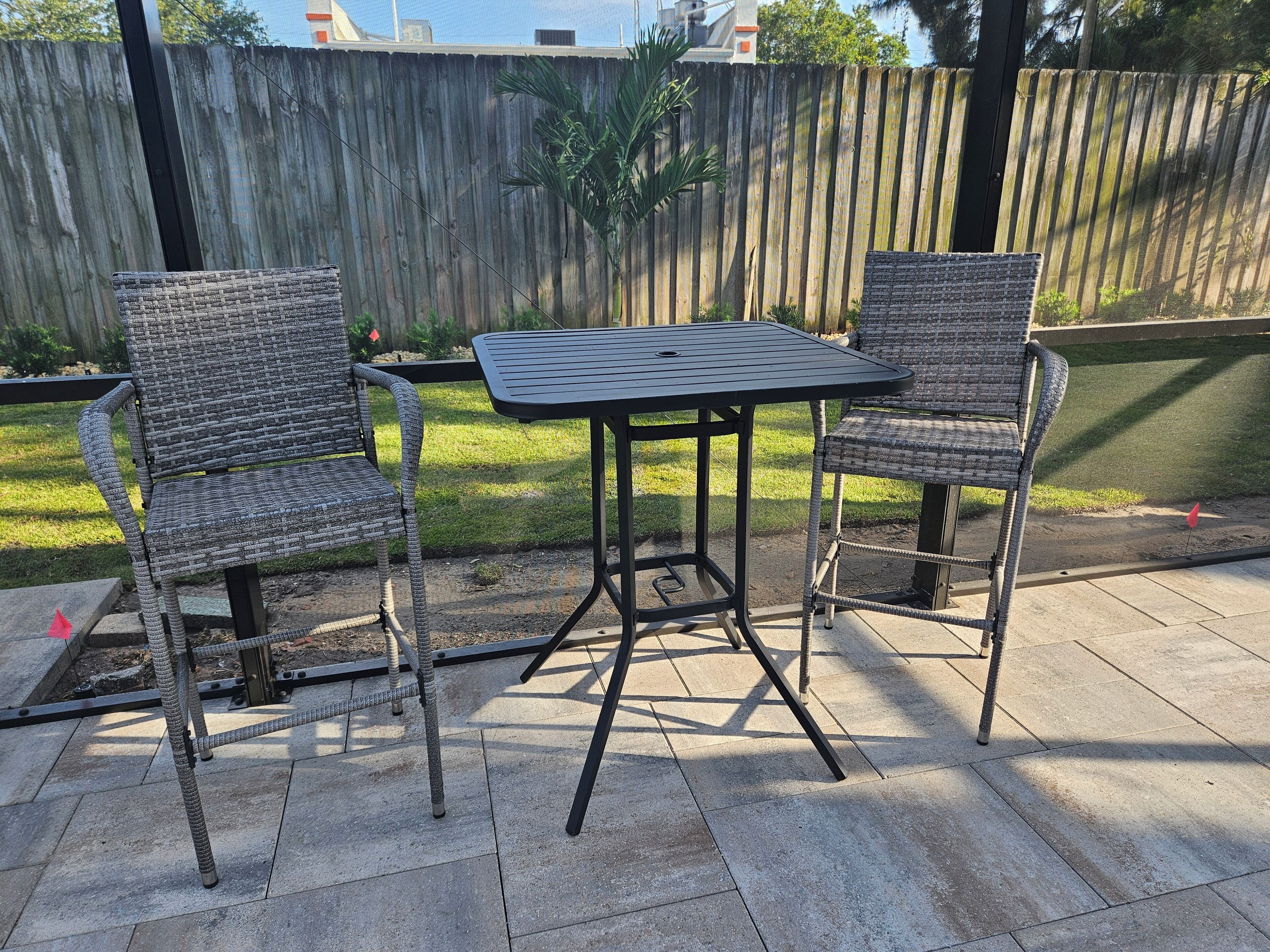 Un patio al aire libre con dos sillas de mimbre y una mesa de metal.