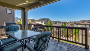 Un patio techado al aire libre con una mesa, sillas, una parrilla y vistas a casas vecinas.
